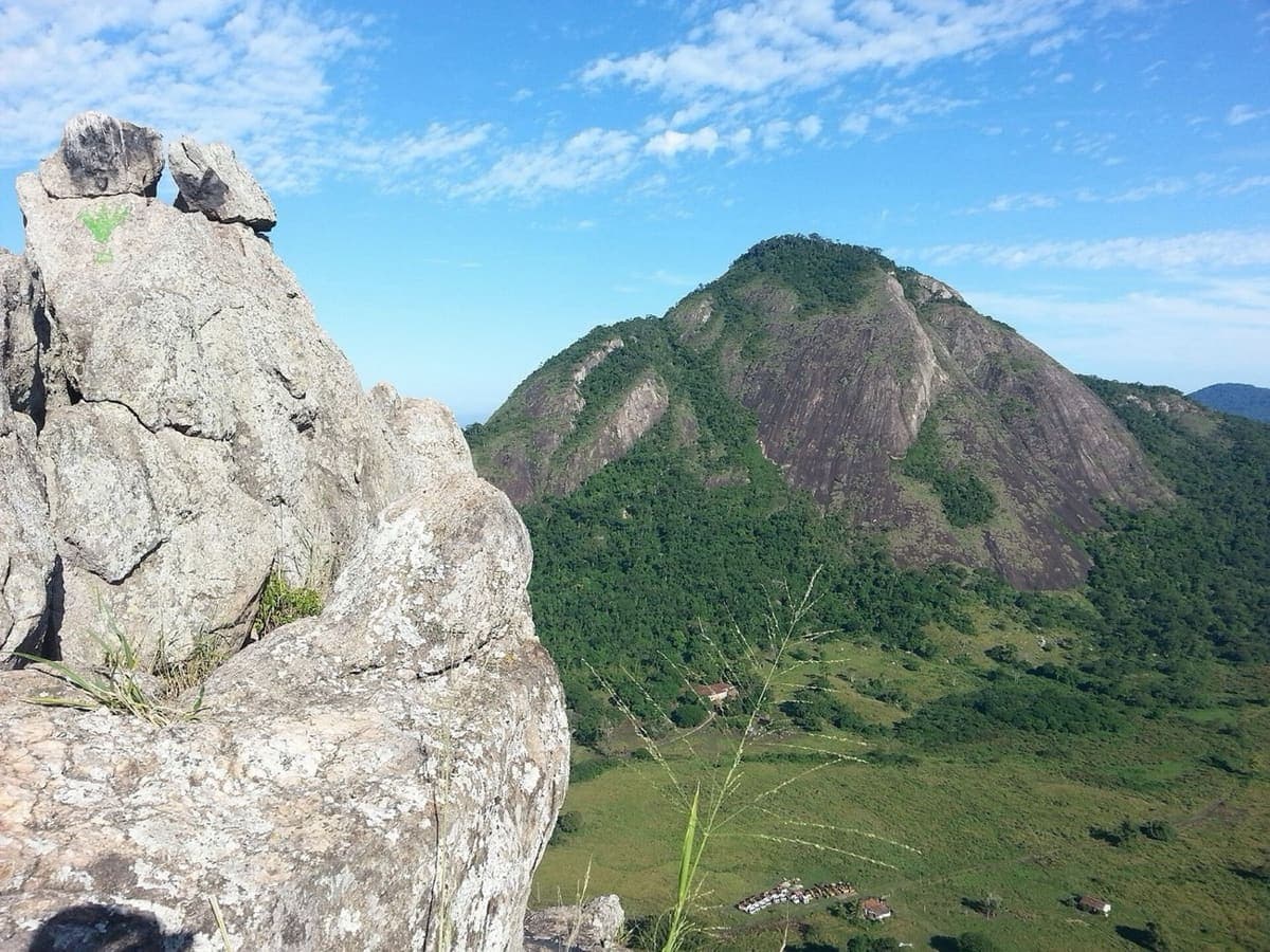 Bloco de granito da Pedra do Macaco, com duas pedras empilhadas no alto e a Pedra de Inoã ao fundo