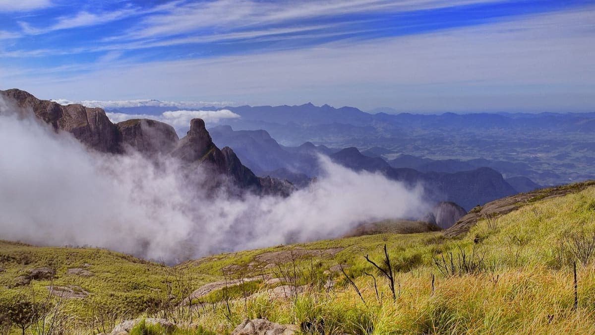 Campos de altitude da Travessia Petrópolis–Teresópolis com nuvens subindo entre os paredões da Serra dos Órgãos